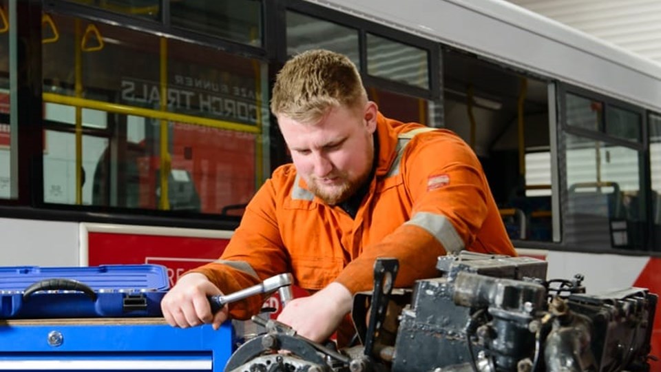 apprentice working on bus engine