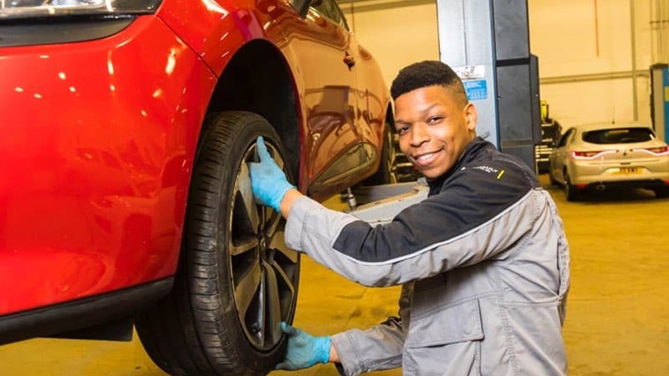apprentice holding car tyre