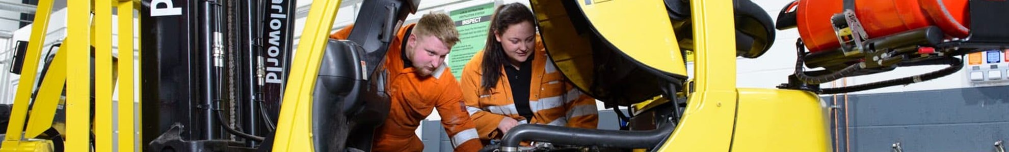 two apprentices inspecting a forklift