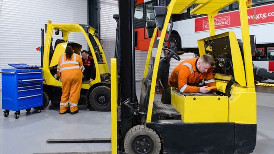 Apprentices working on forklifts